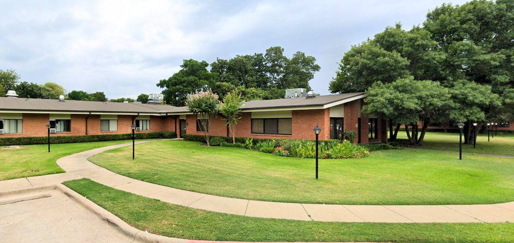 A suburban house with a well-maintained lawn and surrounding trees.