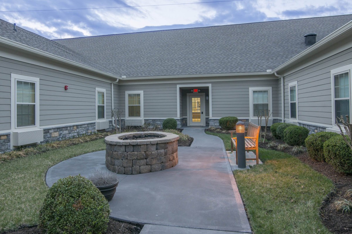 A modern house with a spacious yard featuring a fire pit and landscaping.