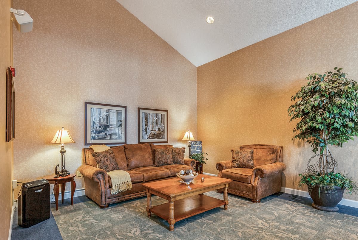 A cozy living room with a sofa, armchair, and coffee table accented by wall art and warm lighting.