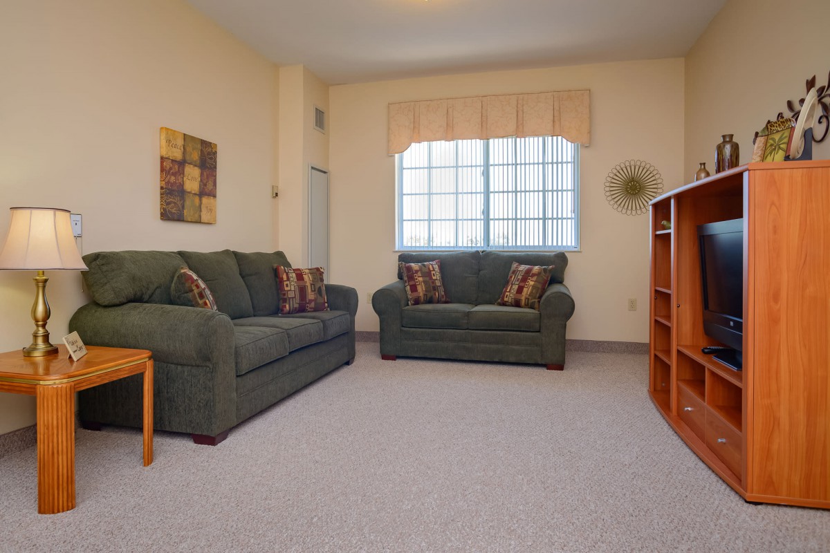 A cozy living room with two sofas, a large window, and carpeted flooring.