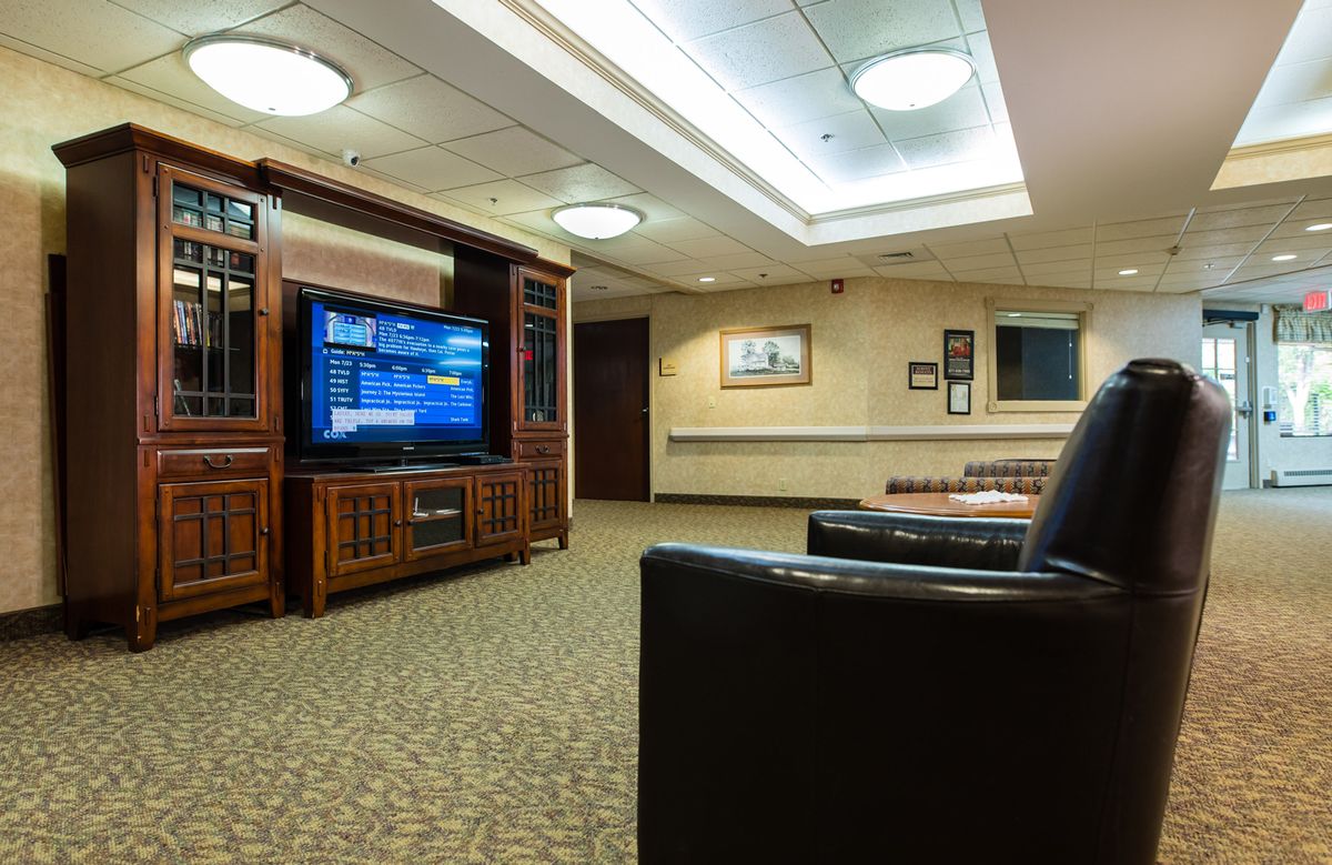 A comfortable waiting room featuring a large television and ample seating.