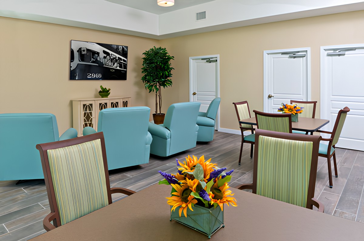 A cozy waiting room with blue chairs, tables, and floral arrangements.