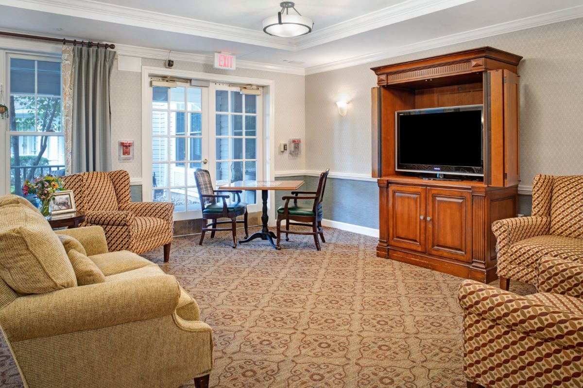 A cozy living room featuring comfortable seating, a table, chairs, and a large TV.