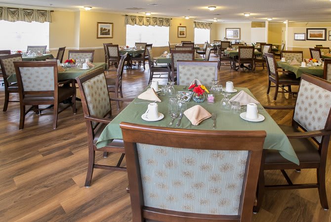 A neatly arranged dining area with tables and chairs, featuring elegant table settings.