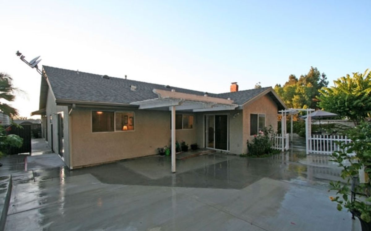 A view of a single-story house with a covered patio in the backyard.