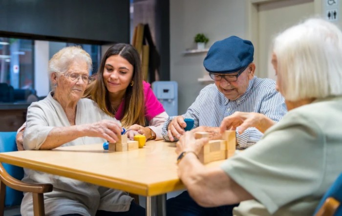 Elderly individuals engaging in activities with a caregiver at a nursing home.