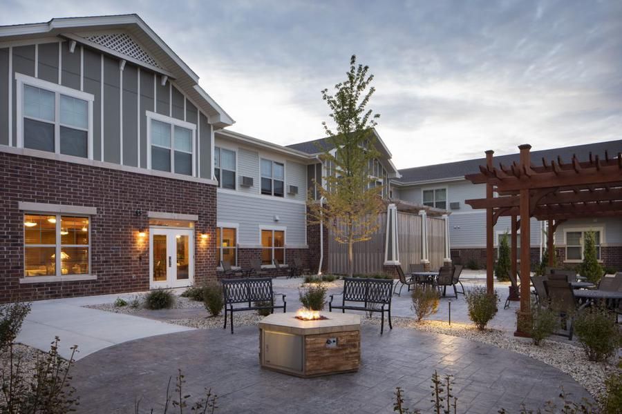 A cozy outdoor patio with seating around a fire pit in front of a modern building at dusk.