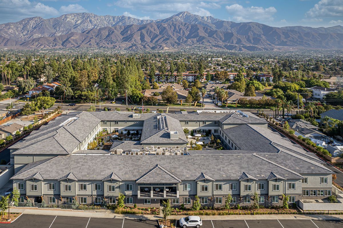 Aerial view of a large building with a mountain backdrop and surrounding suburban landscape.