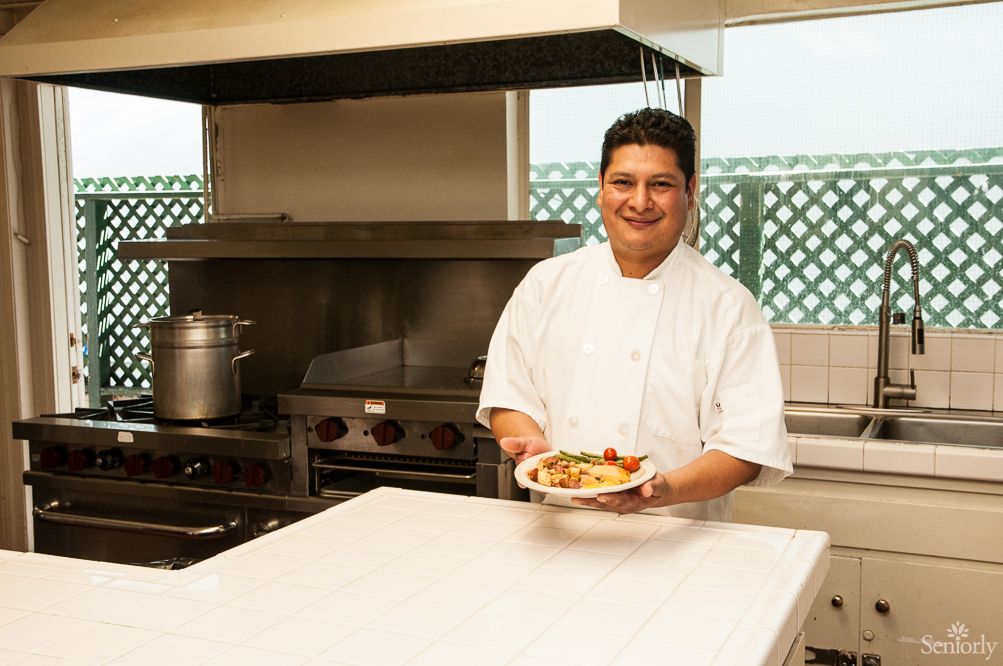 A chef presenting a dish in a professional kitchen.