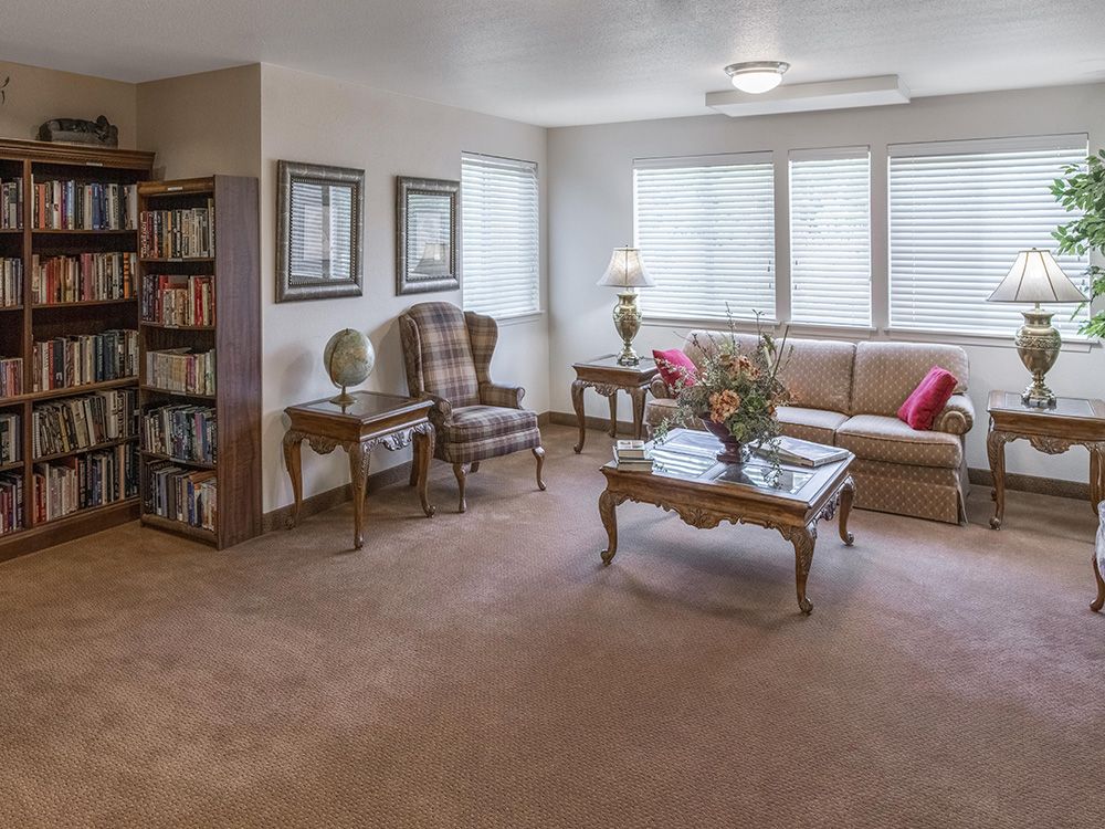 A cozy and elegantly furnished living room with a sofa, armchair, bookshelf, and a coffee table.