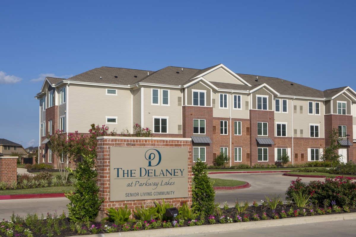 A modern apartment complex named 'The Delaney' with well-maintained landscaping.