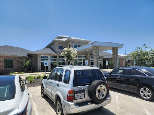 A modern building with a well-maintained exterior and vehicles parked in front.