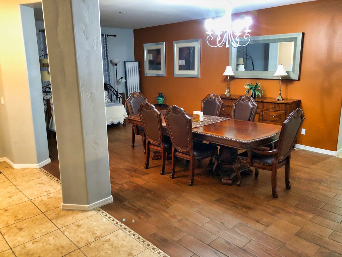 A cozy dining room with a large wooden table set and an elegant chandelier.
