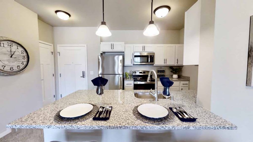 A modern kitchen with stainless steel appliances and a neatly set dining counter.