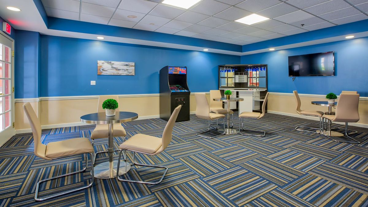 A modern game room featuring an arcade machine, stylish seating, and vibrant blue walls.