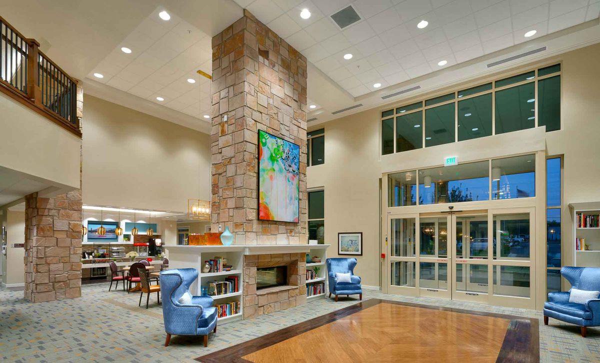 A modern lobby interior featuring a central fireplace, vibrant artwork, and comfortable seating.