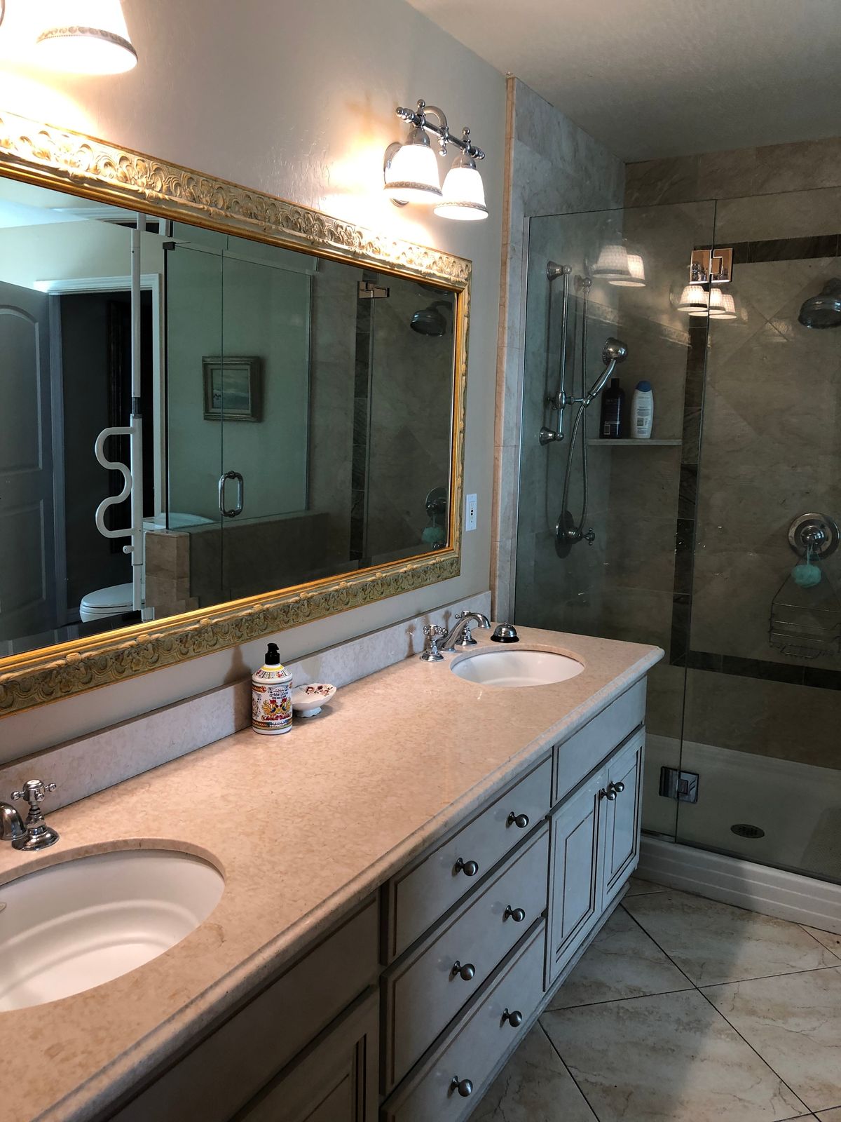 A modern bathroom with a double sink, large mirror, and glass-enclosed shower.