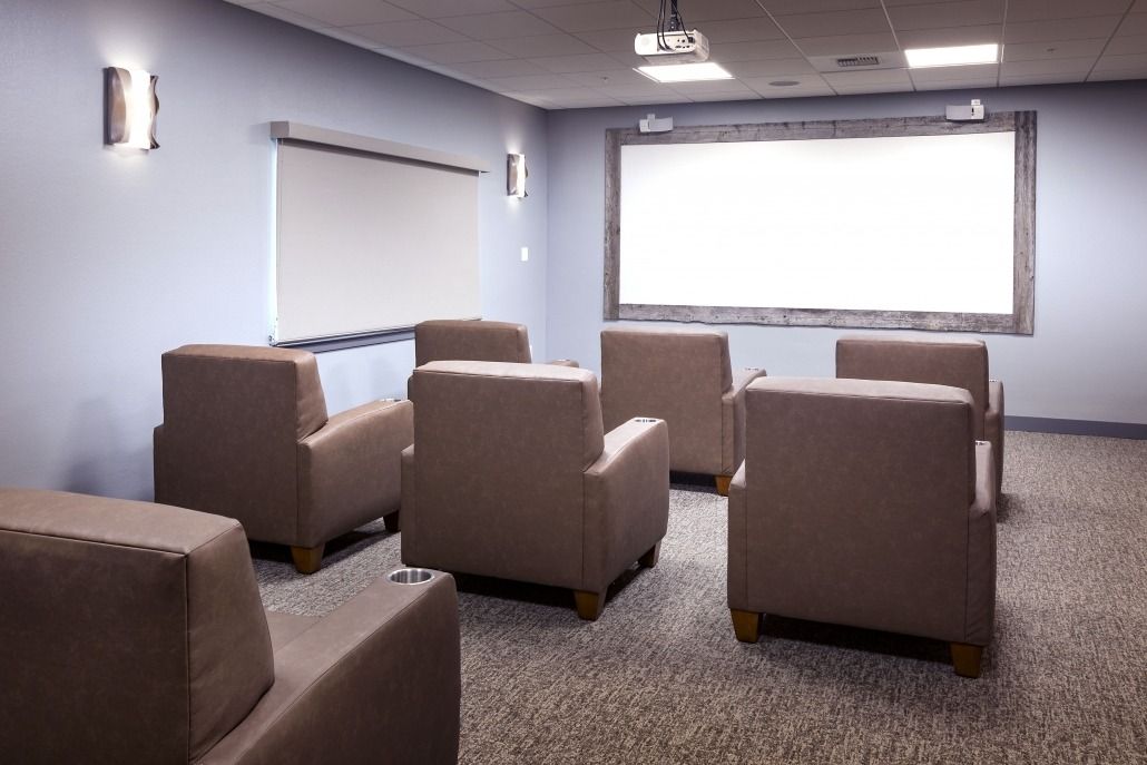 A cozy conference room with comfortable seating and a large projector screen for presentations.