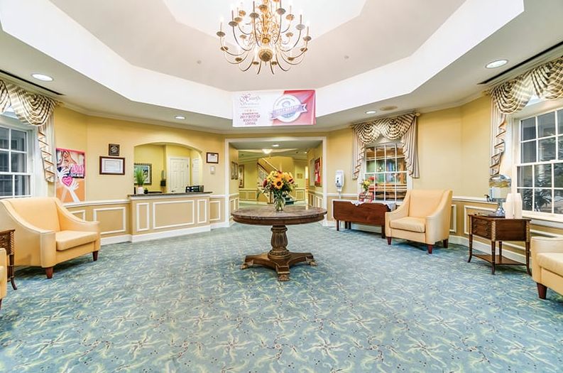 A bright and welcoming lobby with a chandelier, reception desk, and seating area.