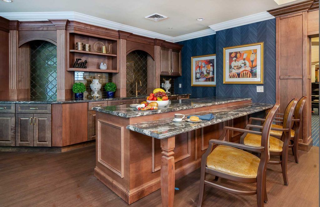 A stylish kitchen with wooden cabinets, a marble countertop, and barstools, complemented by decorative elements and artwork on the walls.