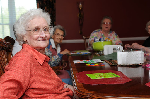 A warm moment captured at a gathering of elderly women enjoying each other's company around the dining table.