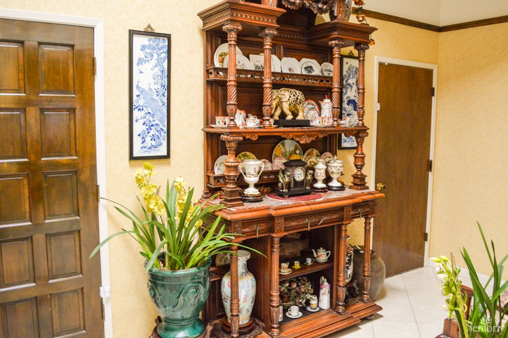 A beautifully crafted wooden shelf adorned with ceramics and decorative items, accompanied by a lush indoor plant.