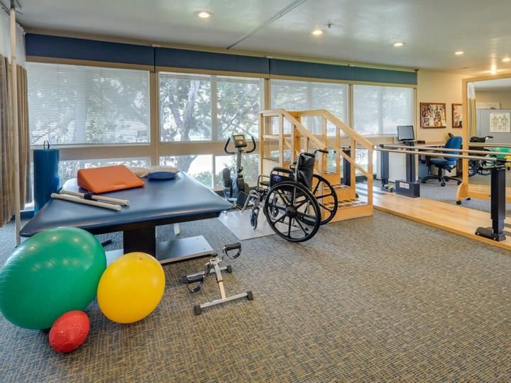 A rehabilitation room equipped with exercise gear and a wheelchair, designed for physical therapy sessions.