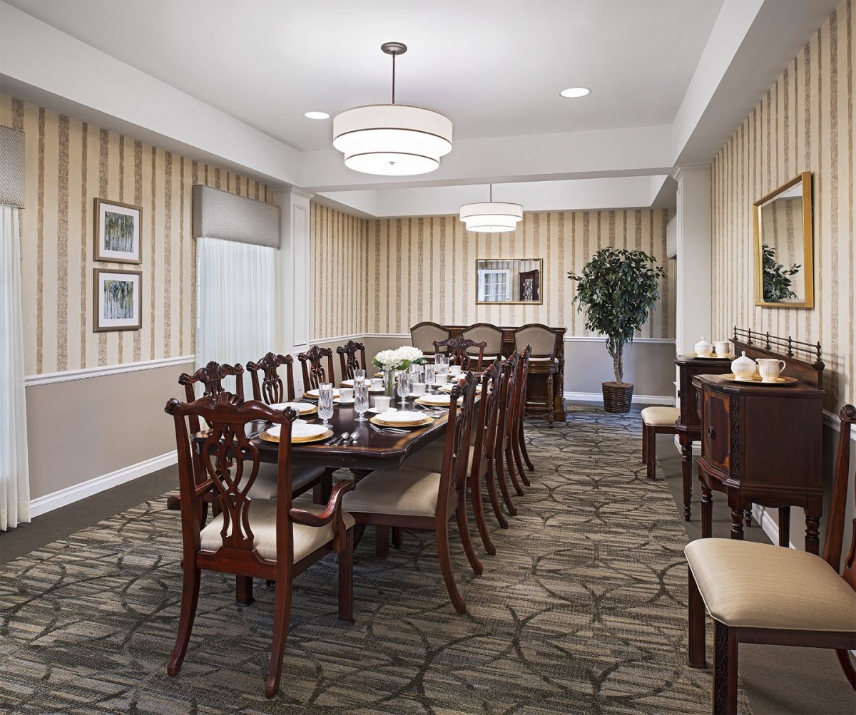 A well-decorated dining room with a long table and chairs, elegantly lit by pendant lights.