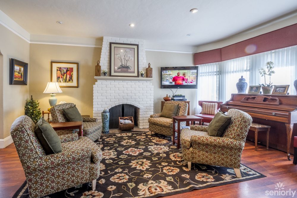 A cozy living room with a fireplace, armchairs, and a television.