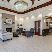 A modern lobby with a seating area, featuring a fireplace and chandelier.