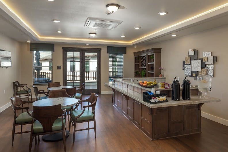 Cozy cafe interior with wood flooring, a coffee station, and seating arrangement.