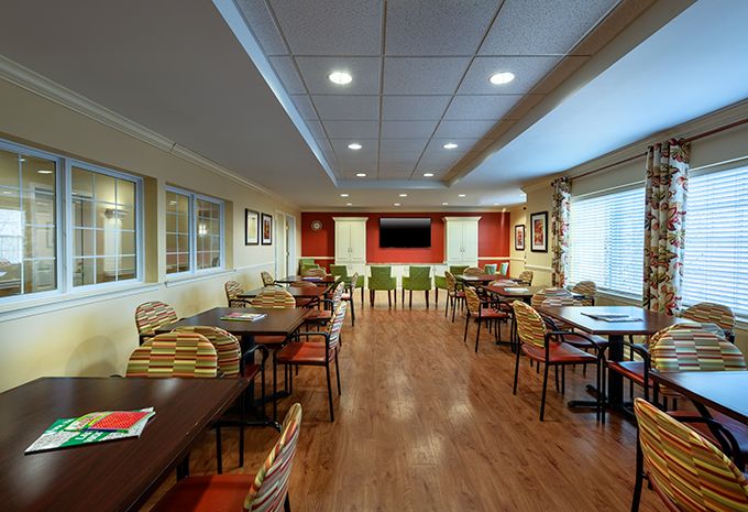 A cozy dining area with wooden flooring and arranged tables and chairs.