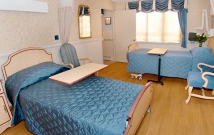 A clean and organized hospital room with two beds and furniture.