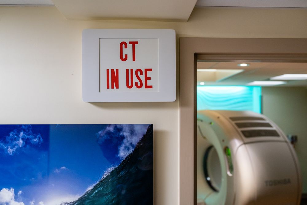 A CT scanner in use sign indicating an active radiology session.