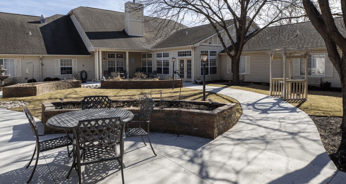 A sunny residential backyard with a patio and seating area.