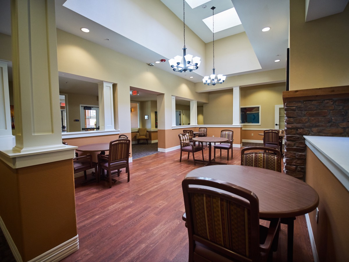 A spacious interior with tables, chairs, skylights, and chandeliers.