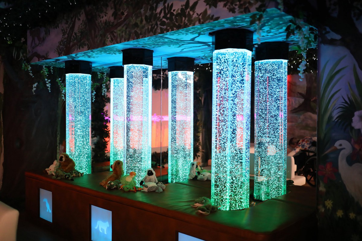 A series of illuminated bubble tubes in a sensory room, creating a calming and colorful atmosphere.