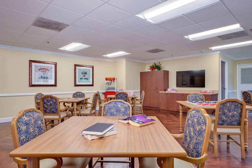 A well-lit room with multiple tables, chairs, artwork on the walls, and a television.