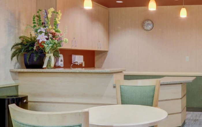 A cozy reception area with a small table, chairs, and decorative flowers on the counter.