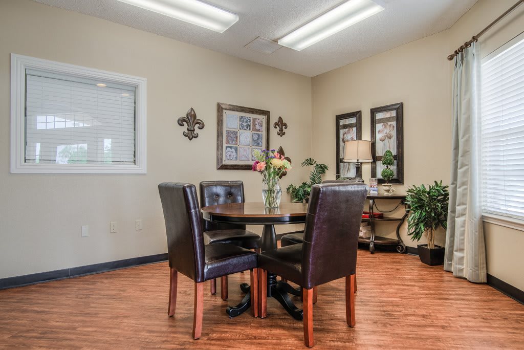 A cozy office meeting room with a round table, four chairs, and decorative elements such as plants and artwork.