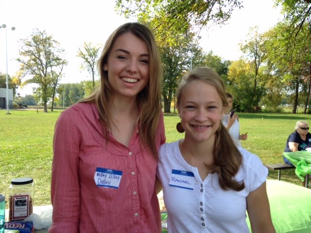 Two people smiling outdoors with name tags, enjoying a sunny day.