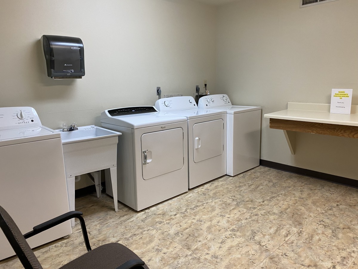 A clean and organized laundry room equipped with washing machines, a dryer, and a sink.