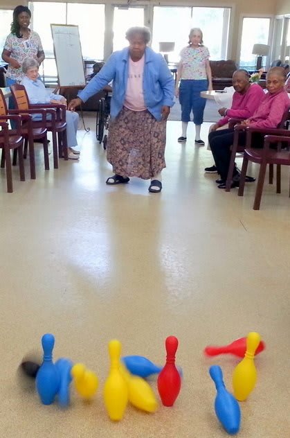 Elderly individuals engaged in a fun indoor bowling activity.