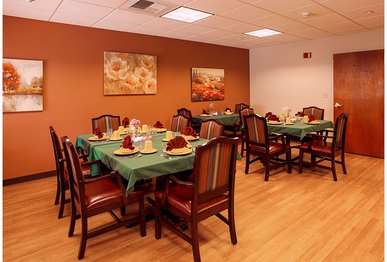 A cozy dining room with neatly arranged tables and chairs, adorned with place settings and wall art.