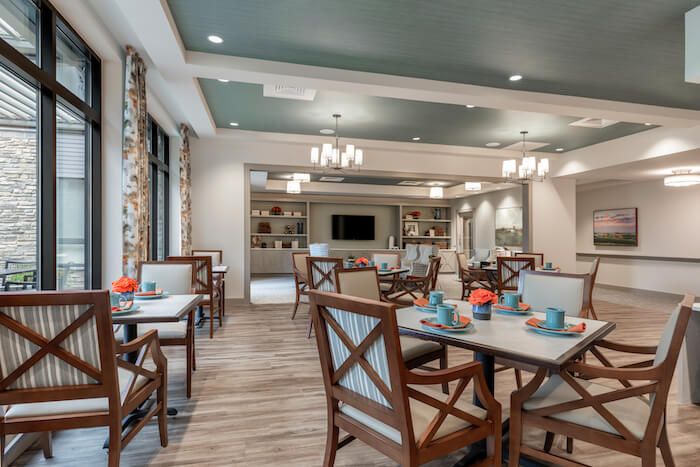 A modern dining area with wooden chairs and tables, featuring elegant lighting and decor.