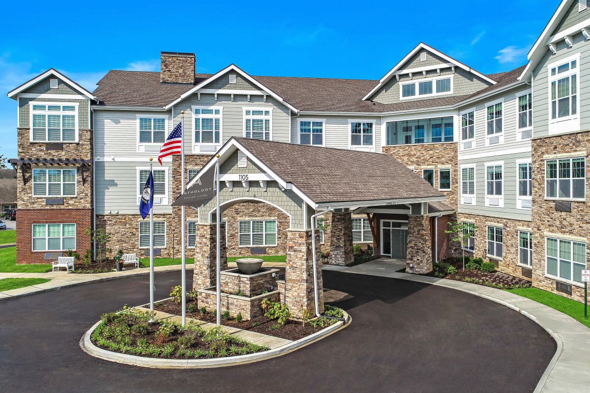 A modern residential building with a stone facade and flags at the entrance.