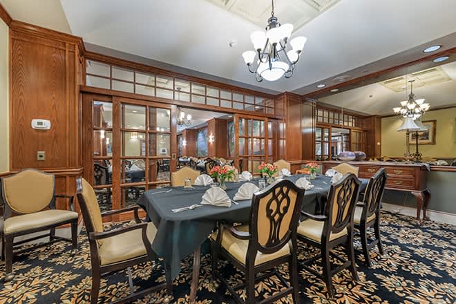 An elegant dining room with a formal table setting and chandelier lighting.