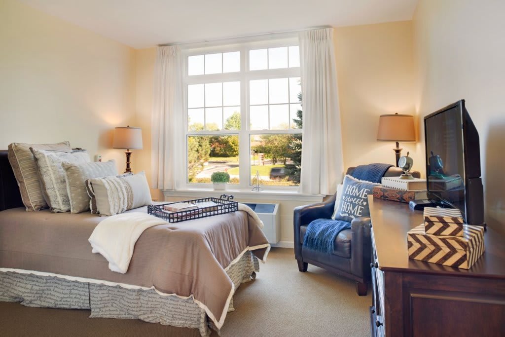 A cozy bedroom with a large window, comfortable bed, and elegant decor.