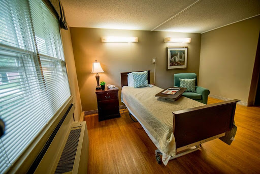 A well-lit hospital room featuring a single bed, comfortable chair, and personal touches to create a welcoming atmosphere.