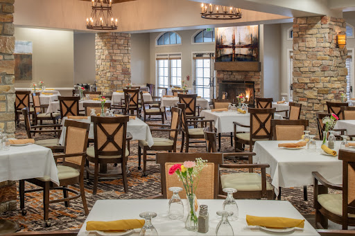 A beautifully arranged dining area featuring elegant tables and chairs, with chandeliers hanging overhead.